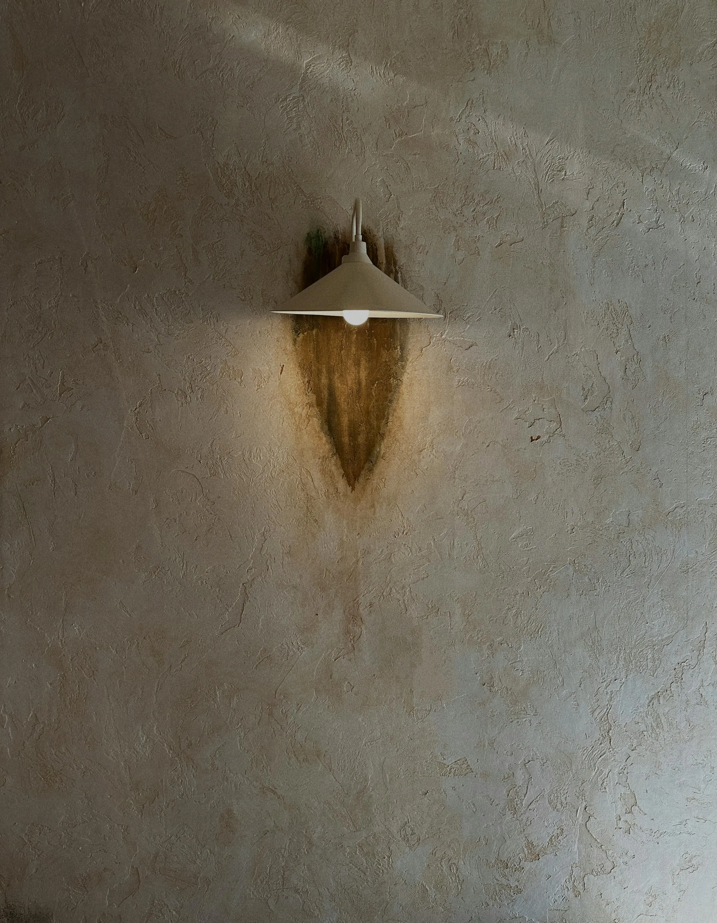 Aplique de pared en latón sobre estuco texturizado